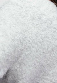 Tela de forro polar gris claro con una superficie suave y texturizada, que presenta una apariencia sutil y esponjosa y un borde liso y redondeado.