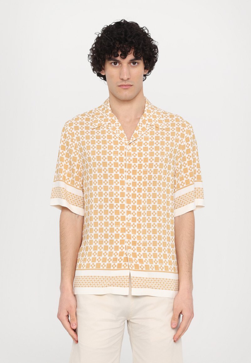 Chemise à manches courtes avec un bouton, de couleur orange clair et à motif carreaux. Tissu doux, avec des poignets et un ourlet contrastants de couleur blanche.