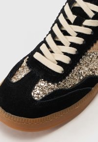 Baskets en suède noir avec des accents de paillettes dorées, des lacets crème et une semelle en caoutchouc naturel. Présente un design texturé et un détail à bords festonnés.
