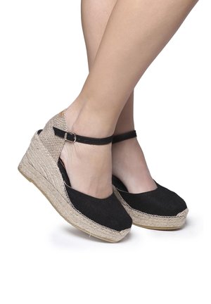 Černé plátěné klínové espadrilky s béžovým pleteným jute středovým podpatkem a páskem kolem kotníku s detailem sponky. Otevřená zadní část.