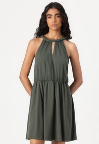 Vestido verde sem mangas com detalhe de pescoço trançado, recorte em forma de chave e cintura elástica. Tecido suave e leve com uma saia fluidas.