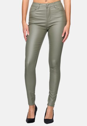 Pantaloni skinny in ecopelle verde oliva con vita alta, tasche frontali e una texture liscia e lucida. Abbinati a tacchi neri.