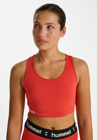 Roter Sport-BH aus elastischem Stoff, mit Rundhalsausschnitt und Hummel-Logo auf dem Band. Nahtloses Design mit figurbetontem Schnitt.