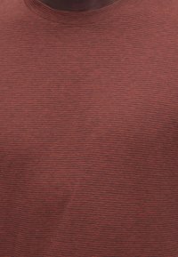 Κοντινό πλάνο από υφασμάτινο ύφασμα με νεύρωση σε σκουρόχρωμο σκουριά χρώμα, με λεπτές οριζόντιες μαύρες ρίγες και στρογγυλεμένη λαιμόκοψη.