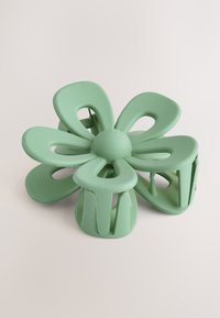 Pince à cheveux en forme de fleur de couleur vert menthe mat. Comprend plusieurs sections semblables à des pétales avec des découpes et une base de prise solide pour une tenue sécurisée.