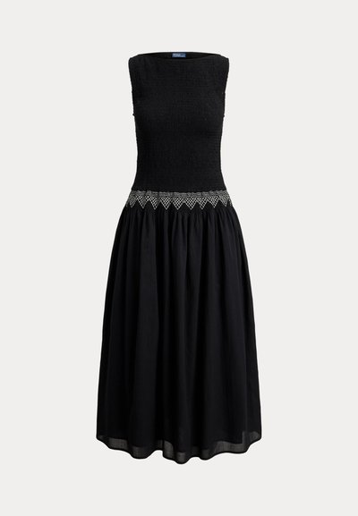 Musta hihaton midimekko, jossa on smokkattu yläosa ja vyötäröllä valkoinen timanttikuviollinen kirjonta, täydentyen leveästi kerrostetulla hameella.