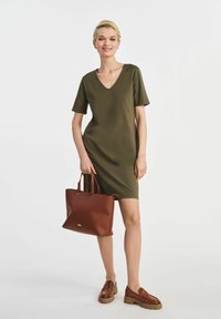 Olive green dress koszulowy z dekoltem w kształcie litery V, krótkimi rękawami i luźnym krojem. Połączony z brązową skórzaną torbą i brązowymi mokasynami.