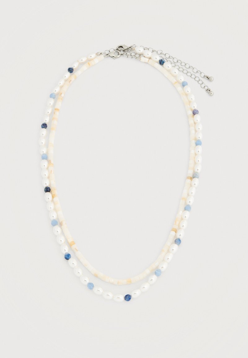 Collier à double rangée avec des perles blanches et beige clair, agrémenté de petites perles bleu clair et bleu foncé, fermé par un fermoir en argent et une chaîne réglable.