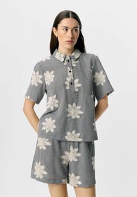 Chemise à manches courtes à carreaux noir et blanc avec broderie florale, dotée d'un col et d'une patte de boutonnage, associée à un short assorti.