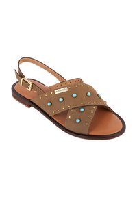 Bruine suède sandaal met gekruiste banden, gouden studs en turquoise accenten. Heeft een slingback ontwerp en een platte zool. Verstelbare gesp sluiting.