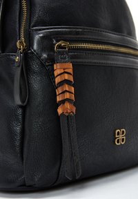 Mochila de cuero negro con un acabado texturizado, que presenta una cremallera dorada y un borlas decorativa de cuero en marrón y beige.