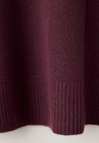 Tissu en laine violet foncé avec un motif en maille côtelée au bord inférieur.
