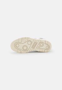White sneaker sole with textured rubber, featuring a beige outsole. Includes circular and linear patterns with brand logo embossed.