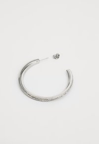 Sølv hoop ørering med teksturert detaljer, med en rett stang og et sommerfugl-bakstykke. Glatt overflate med intrikate mønstre langs kanten.