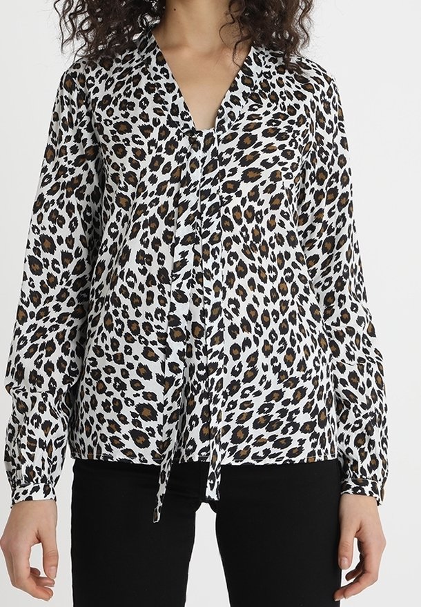 Leopardskinnad blus i vitt, svart och brunt, med långa ärmar och en knytframsdetailj. Tillverkad av mjukt, lätt tyg.