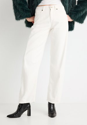 Witte jeans met een hoge taille en een rechte pijpvorm, subtiele stiksel details, gecombineerd met zwarte puntige enkellaarsjes.