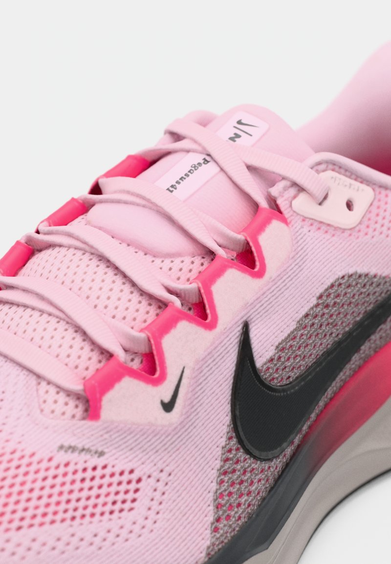 Light pink athletic shoe featuring mesh upper, pink accents, black logo, and a molded gray midsole with textured detailing.