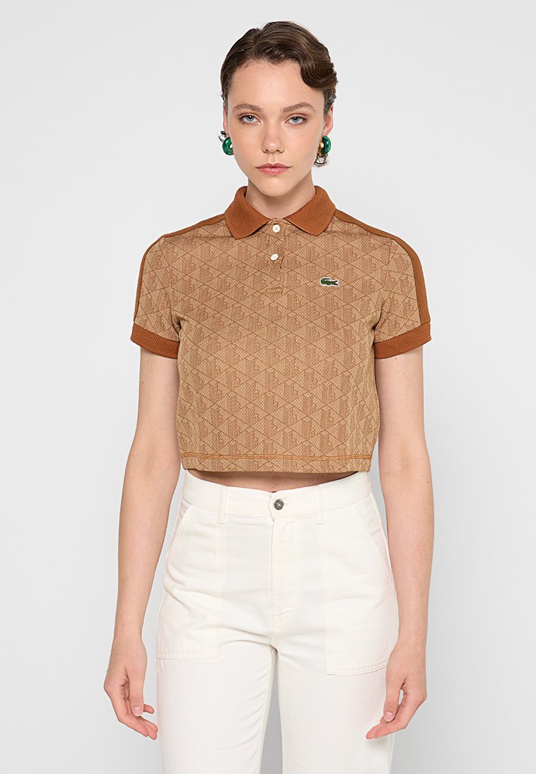 Polo shirt corto marrón con patrón y acabado texturizado, cuello y puños en contraste, y un pequeño logo verde en el pecho.