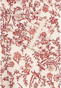 Gros plan sur un tissu avec un motif floral rouge et rose, présentant un poignet avec trois boutons blancs et une finition en dentelle.