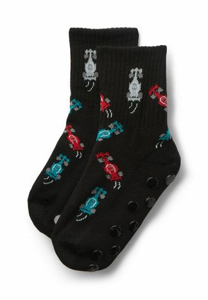 Schwarze Socken mit roten, blauen und weißen Rennwagenmustern und schwarzen rutschfesten Sohlen.
