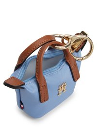 Μικρή μπλε υφασμάτινη τσάντα χειρός με καφέ δερμάτινες λαβές και χρυσά εξαρτήματα, με κλείσιμο με φερμουάρ και διακριτική τυπωμένη λογότυπη λεπτομέρεια.