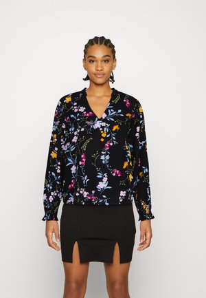 Blusa floral com fundo preto, apresentando mangas longas, decote em V e padrões florais coloridos em tons de rosa, amarelo e azul.