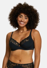 Soutien-gorge noir à armatures avec dentelle et détails en feston, présentant une texture côtelée et une ouverture centrale, accompagné d'un bas assorti.