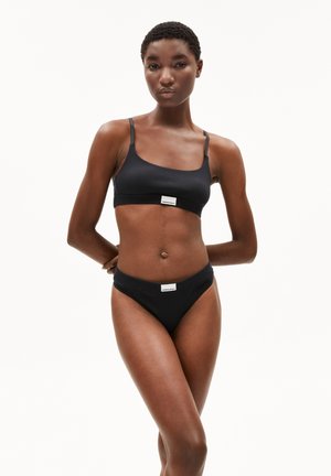 Zwarte bralette en bikini set van zacht materiaal. De bralette heeft dunne bandjes en een logo label; de bikini heeft een middelhoog snit met een vergelijkbaar label.