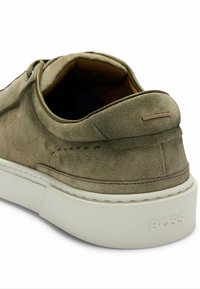 Olive green suede shoe with a rounded shape, white platform sole, and muted stitching. Features logo on the heel and minimalistic design.