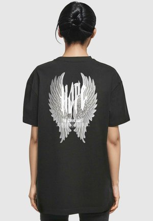 Black oversized t-shirt featuring large white angel wings and the text "HOPE" on the back. Soft cotton fabric with a relaxed fit.