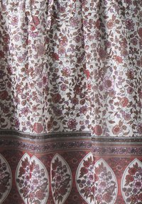 Maximekko, jossa on kukkakuvio, joka sisältää vaaleanpunaisen, ruskean ja valkoisen sävyjä. Kangas on kevyt ja virtaava, ja siinä on yksityiskohtainen helmareunus.