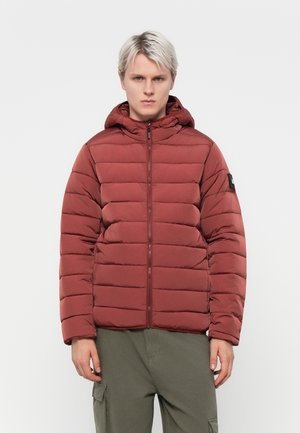 Rød puffer jakke med horisontalt quiltet mønster, hette, frontlås og en patch detalj på venstre erm. Glatt tekstur.