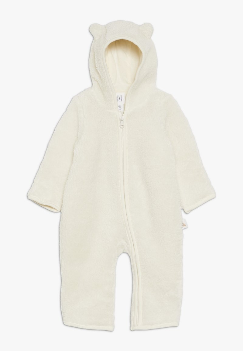 Grenouillère bébé couleur crème, duveteuse, avec capuche, petites oreilles d’ours et fermeture éclair à l'avant.