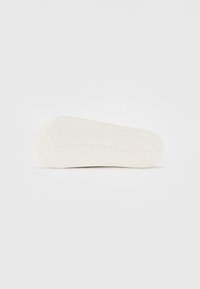 Semelle de chaussure en caoutchouc blanc avec une surface texturée et un motif de grip. Forme courbée avec une base plate, conçue pour le confort et la durabilité.