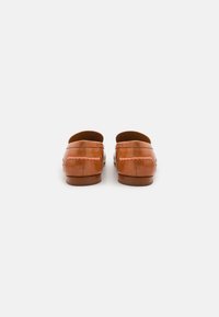 Barna bőr slip-on cipők sima felülettel, kerek orral, és látható varrással a széleken. Lapos fa talp.