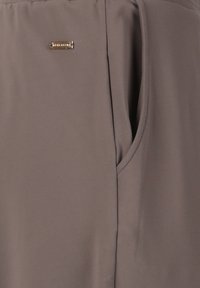 Grauer Stoff mit glatter Textur und drapierter Optik, mit einer Seitentasche und einem kleinen goldenen Logo-Detail.