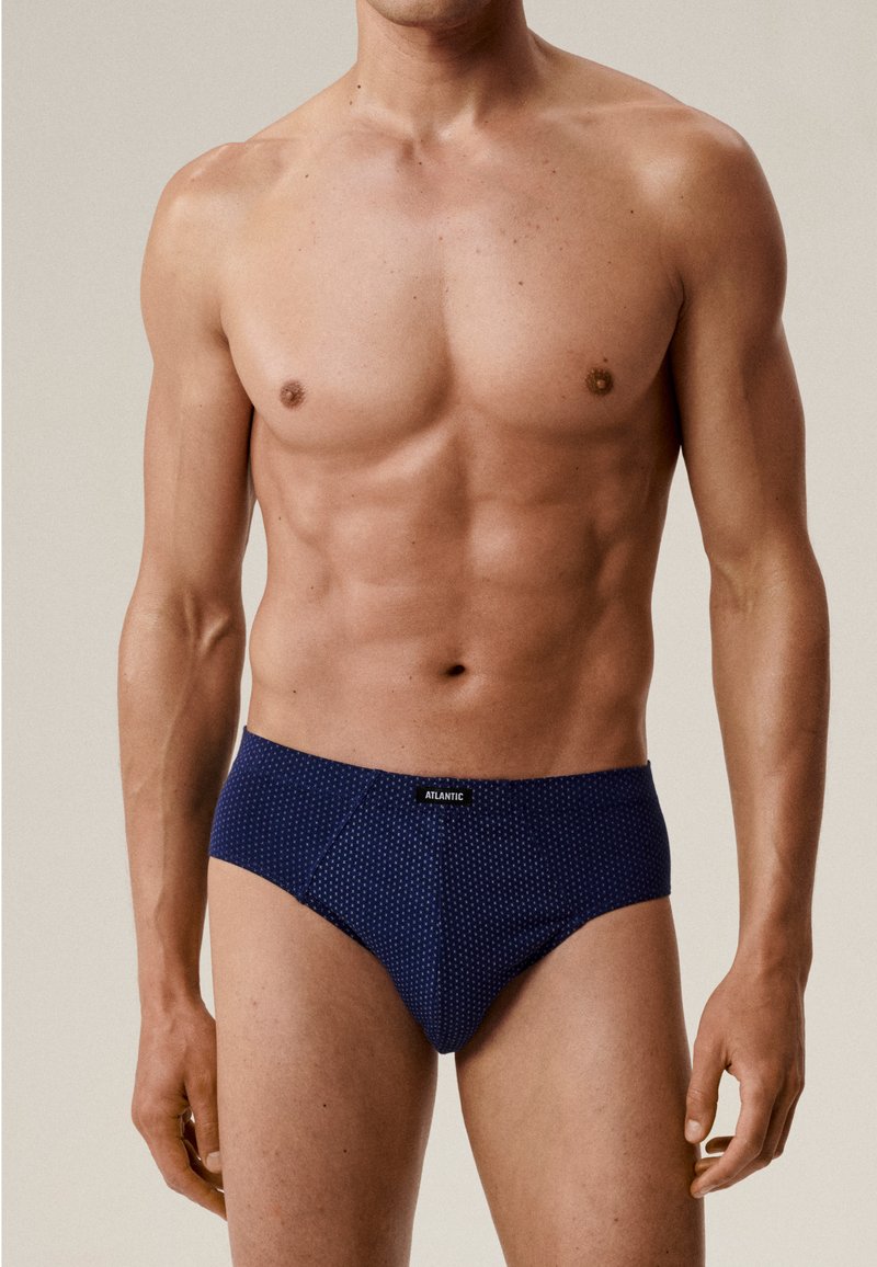 Granatowe kąpielówki z małym białym wzorem w kropki, z kontrastującym elastycznym pasem oznaczonym "ATLANTIC". Gładka tekstura materiału.