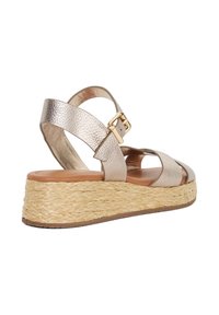 Metallic gold platform sandal with textured straps and a natural woven jute sole. Features a buckle closure and open toe design.