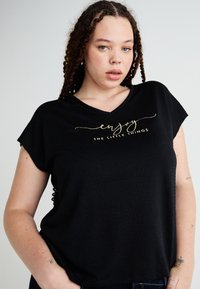 Μαύρο μπλουζάκι με κοντά μανίκια και V-ντεκολτέ, textured ύφασμα, με χρυσά καλλιγραφικά γράμματα που αναγράφουν "απόλαυσε τα μικρά πράγματα."