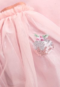 Tessuto in tulle rosa con parte superiore arricciata e un motivo decorativo a ananas con paillettes nei toni argento, rosa e verde.