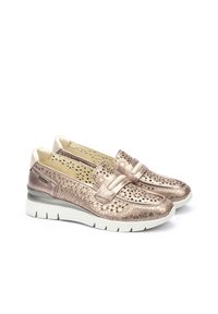 Zapatos slip-on de color oro rosa metálico con diseño perforado y una correa frontal. Presentan una suela de goma blanca con acentos texturizados.