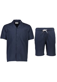Marineblauwe overhemd met korte mouwen en knoopsluiting, voorzien van twee borstzakken, en bijpassende shorts met een elastische trekband in de taille, gemaakt van gestructureerde stof.