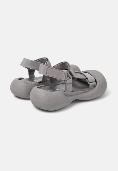 Gray outdoor sandals with a textured rubber sole, adjustable fabric straps, and a cushioned footbed. Rounded toe design for comfort.