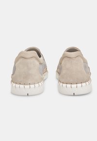 Beige nubuk- ja võrgusneakerid, millel on ümar kuju, valge õmblusega välistald ja pehmed tagaosad mugavuse ja hingavuse tagamiseks.