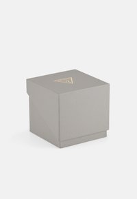 Hallide tekstuuriga hall kast, mille peal on kolmnurkne kullast logo. Ruudu kujuline, volditud kaane disainiga, millel on puhtad jooned ja minimaalsed aktsendid.