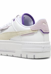 Sneaker in pelle bianca con accenti in suede viola e beige, suola intermedia testurizzata, collare imbottito di supporto e logo sul tallone.