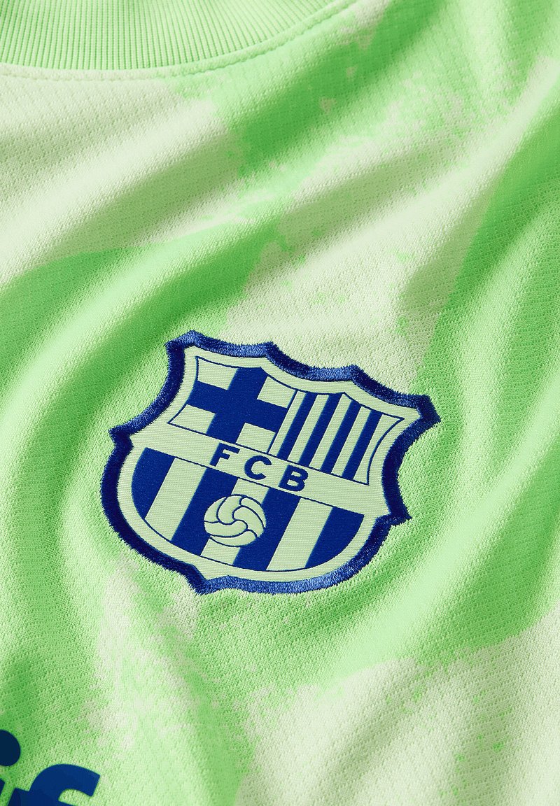 Neon-grüner Stoff mit einem gestickten blauen und weißen FC Barcelona-Wappen, das in der Mitte von Streifen und einem Fußball-Graphic umgeben ist.