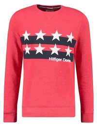 Sudadera roja de manga larga, con un patrón de estrellas en negro y blanco y el texto "Hilfiger Denim" en el pecho. Material de mezcla de algodón.