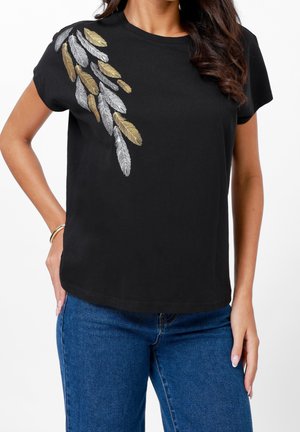 Zwart T-shirt met korte mouwen en een geborduurd ontwerp van metalen gouden en zilveren veren op de linkerschouder, met een ontspannen pasvorm.