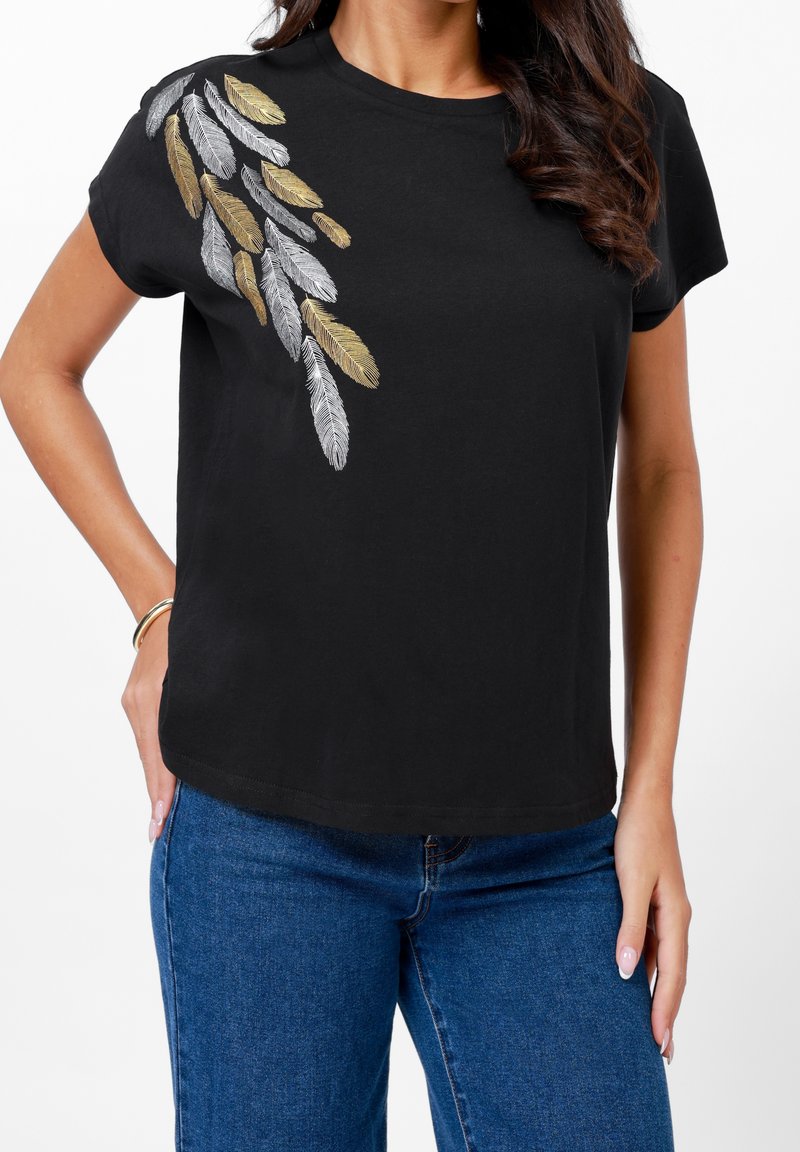 T-shirt noir à manches courtes avec un motif brodé de plumes métalliques dorées et argentées sur l'épaule gauche, doté d'une coupe décontractée.